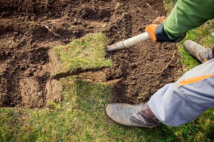 Person legt Rasenstücke mit Spaten aus